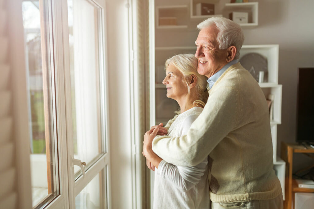 SoCo Village | Senior couple looking at the view out their new apartment window after downsizing