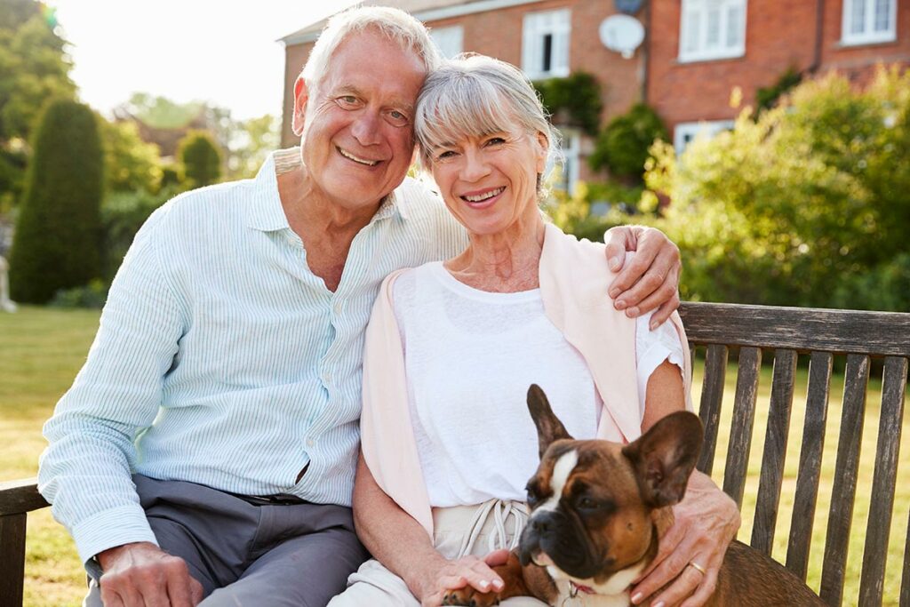 SoCo Village | Happy senior couple sitting on bench with dog