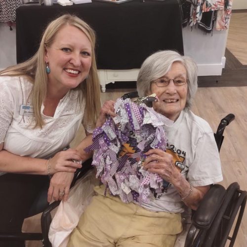 SoCo Village | Associate smiling beside senior woman as she shows off a handcrafted wreath